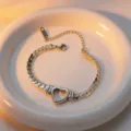 Close-up detail of the elegant hollow heart Cuban chain bracelet on a white ceramic plate. - Bracelet / Silver