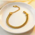 Elegant gold-tone herringbone chain bracelet detailed with delicate extension and lobster clasp. - Bracelet