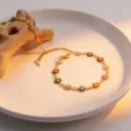 Close-up detail of colorful enamel daisy flower gold-plated chain necklace or bracelet display. - Colorful Daisy Bracelet Gold