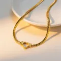 Close-up detail of the gold flat snake chain necklace featuring a hollow heart pendant. - Necklace / Gold