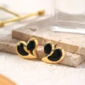 Detailed close-up of gold-plated heart titanium steel earrings with black enamel inlay texture. - Black