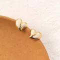 Detailed shot of gold-plated titanium steel heart earrings with white enamel finish. Close up. - White