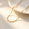 Detailed shot of a sleek gold-plated wavy chain necklace, elegant and modern everyday jewelry. - Necklace / Gold