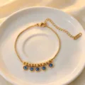 Gold stainless steel evil eye pendant bracelet detail close-up view, delicate chain links. - Bracelet / Gold