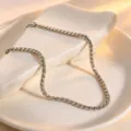 Detailed closeup of the elegant silver rope chain jewelry displayed on a white ceramic tray. - Necklace / Steel