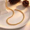 Close-up view of the golden twisted chain necklace beautifully displayed on a white ceramic plate. - Necklace / Gold