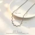 Detail shot of wavy stainless steel necklace on white plate, featuring unique ripple design. - Necklace / Steel