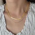 Close-up detail shot of a double layer gold plated herringbone snake chain necklace on neck. - Double Layer Flat & Thin Snake Chain