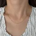 Close-up detail view of the elegant 18k gold plated thin chain necklace worn on neck. - O Chain