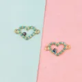 Detailed close-up of gold heart charms with blue evil eye and turquoise beads for DIY crafting. - Heart with Christmas Tree / 10 Pieces/Pack