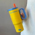 Detailansicht des isolierten Edelstahlbechers mit ergonomischem Griff und buntem Trinkhalm. - 24oz / Dunkelblau