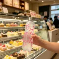 Mattierte Kunststoff-Wasserflasche mit rosa Schleifenmuster in einer Bäckerei gehalten. - Rosa Schleife 1000ml