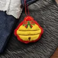 Close-up detail shot of a cute Christmas bell plush pendant with red bow and hanging chain. - Chain Style / Christmas Bell