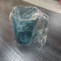 Blue plastic mouthwash cup with handle, transparent protective wrapping for daily use. - Blue