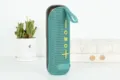 Vue détaillée de l'enceinte Bluetooth sans fil portable avec maille en tissu cyan et sangle. - Vert