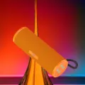 Tragbarer kabelloser Bluetooth-Lautsprecher mit leuchtend orangenem Stoffnetz und Band. - Orange