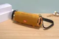 Nahaufnahme des tragbaren Bluetooth-Lautsprechers mit orangefarbenem Stoffnetz und Bedienelementen. - Gold