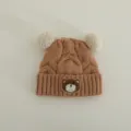 Infant knit beanie detail, brown cable knit texture with cute bear patch and fluffy pom poms. - Suggested 1-3 Years (46-50cm) / Khaki