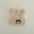 Cute baby knitted hat with double pom poms and cute bear patch, warm winter beanie for kids. - Suggested 1-3 Years (46-50cm) / Beige