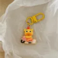 Close-up detail of a cute yellow cartoon animal keychain pendant riding a pink scooter accessory. - Cute Capybara - Cycling