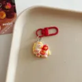 Detailed shot of a cute cartoon horse keychain with red metal clasp on a beige tray. - Horse - Auspicious