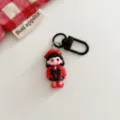 Close up detail of the dark gothic cartoon girl keychain pendant with red and black design. - Dark Girl - Wearing Hat