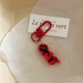 Close-up detail of the cute black cat keychain with a red clasp, charming bag accessory gift. - CAT Tag