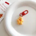 Cute gingerbread man keychain with red clasp on white plate, perfect bag charm gift. - Gingerbread Man