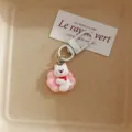 Close-up detail of the cute white puppy keychain pendant with pink flower and red scarf. - Westie Dog - Pink Sofa