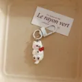 Cute white dog keychain pendant detail closeup showing glossy finish and red bow decoration. - Westie Dog - Sleeping
