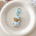 Detail shot of a cute cartoon sleeping bear keychain hanging ornament with blue pajamas. - Blue Bear in Pyjamas