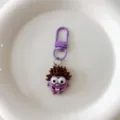 Close-up detail of funny cartoon monster keychain pendant with purple clasp and messy hair. - Purple