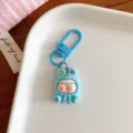 Détail du porte-clés personnage cartoon bleu, montrant une poupée dodue et un mousqueton en métal. - Bleu