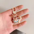 Cute cartoon cat keychain pendant closeup, stylish bag charm accessory for student use. - Beige