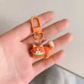 Close-up of a cute orange cat keychain with metal clasp, detailed design, perfect bag accessory. - Orange