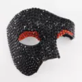 Detalle en primer plano de una máscara negra cubierta de brillantes con borde de ojo rojo. - Media Cara de un Ojo Negro/Rojo