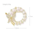 Close-up detail of the elegant gold pearl butterfly brooch, featuring sparkling rhinestones. - Gold