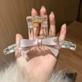Detailansicht der klaren Acryl Haarklammer mit rosa Schleife und edlem Metallakzent. - Transparent Rosa Schleife
