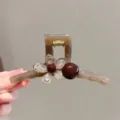 Nahaufnahme einer stilvollen teafarbenen Acryl Haarklammer mit Blume und brauner Perle. - Linearer Einzelperlen Stil (6#)