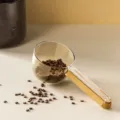 Cuchara medidora multifuncional para mascotas con mango de madera y escala clara. - Caqui