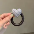 Primer plano del detalle de coletero de pelo con corazón de cuadros, accesorio azul amarillo - Azul claro