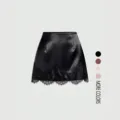 Detail view of the black satin mini skirt featuring elegant lace hem and color options. - S / Black