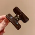 Primo piano del morsetto per capelli in acetato marrone a forma di H con fiocco dorato. - Pinza Capelli Fiocco H / marrone cioccolato