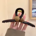 Detailansicht der eleganten braunen Haarklammer mit stilvollem Perlendesign für Frisuren. - Schokobraun