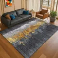 Detailed view of modern grey and gold abstract patterned area rug styled in living room setup. - Gilded