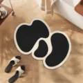 Detailed scene of abstract irregular black and white diatomaceous earth floor mat on wooden floor. - Lost Heartbeat