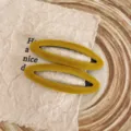 Detailaufnahme gelber Samt-Haarspangen in ovaler Form, die die weiche Textur und das Design zeigen. - Basismodell (Einzelstück) / Gelb