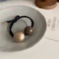 Detailed close-up view of the minimalist dual-ball hair tie with glossy gold and brown beads. - Ball Hair Tie (B63-1) / Champagne