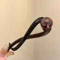 Detail view of the brown pearl hair claw clip, featuring a glossy twist design and smooth finish. - Twist Clip / Translucent Amber