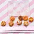 Detailed view of miniature pineapple bun silicone mold with finished resin charms and size ruler. - Clay Pineapple Bun Silicone Mold